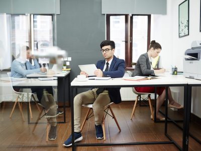 Busy modern open plan office: talented young designers sitting at desks and working on promising project, room illuminated with daylight